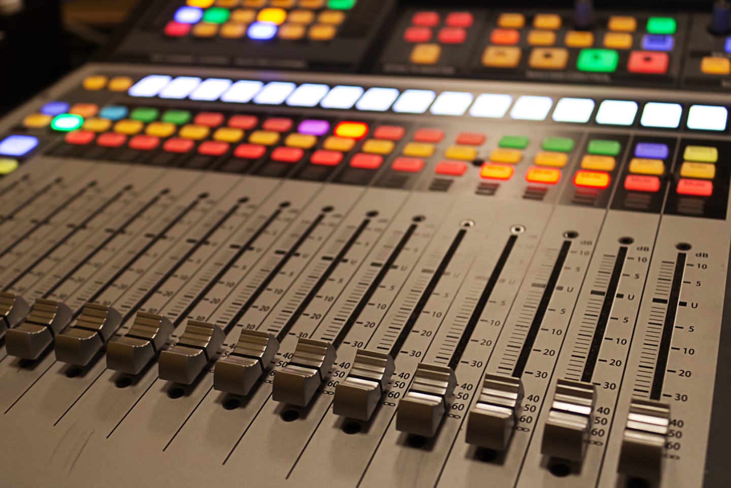 Console de mixage audio professionnelle avec boutons et faders illuminés.