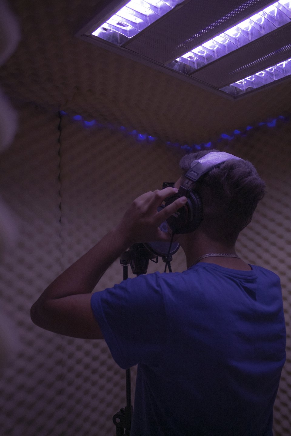 Une personne porte un casque et enregistre de l'audio dans une cabine acoustique.