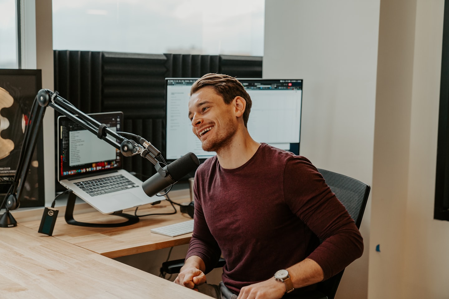 Un jeune homme rit en enregistrant un podcast en studio.
